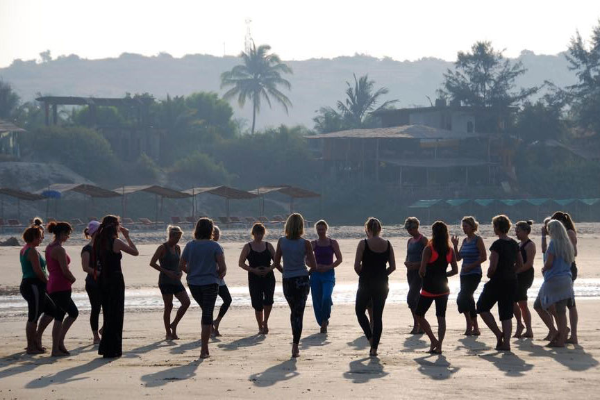 Kirsten Slots underviser gruppen i balanceøvelse på stranden i Goa på yogarejse